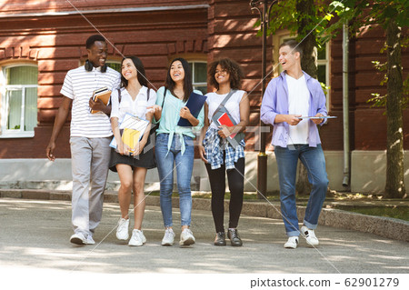 Group of students walking outdoors in university campus together 62901279