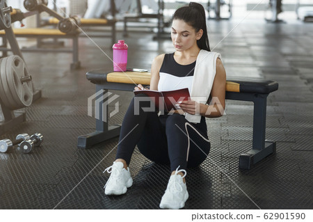 Attractive woman with notebook planning her workout schedule in sports club 62901590