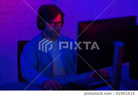 Gamer At Computer Playing Shooter Games Sitting In Dark Room Gamer At Computer Playing Shooter Games Sitting In Dark Room 62901614