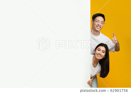 Asian happy couple standing next to empty advertising board 62901756