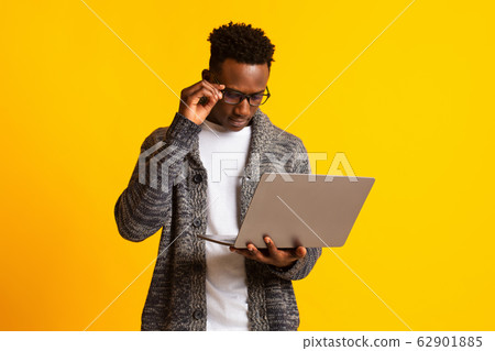 Pensive young african guy freelancer looking at his laptop 62901885
