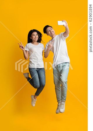 Beautiful asian couple taking selfie while jumping up 62901894