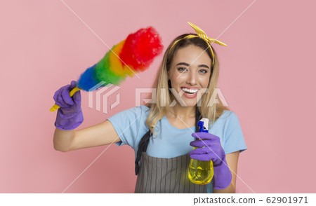 Smiling girl holds colorful duster brush and threatens with spray Smiling girl holds colorful duster brush and threatens with spray 62901971