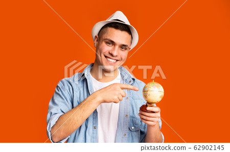 Young tourist holding globe, pointing to desirable destination of trip 62902145