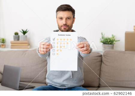 Happy young man holding customer review with five star rating Happy young man holding customer review with five star rating 62902146