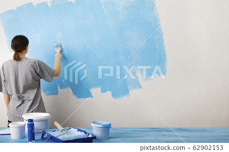 Girl puts the first layer of blue paint Girl puts the first layer of blue paint 62902153