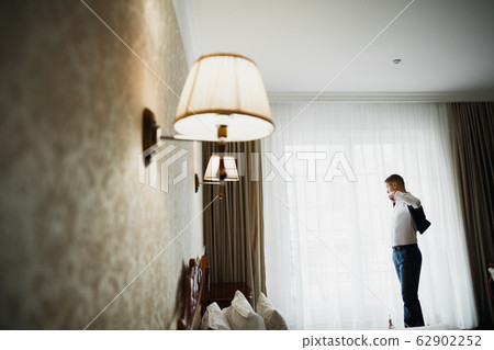 Grooms morning preparation. Handsome man getting dressed and preparing for the wedding 62902252