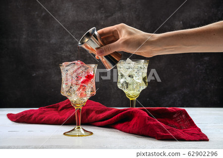 Hand of bartender with jigger pouring cocktail 62902296