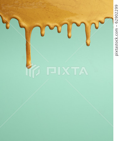 Golden paint dripping on green background, copy space 62902299