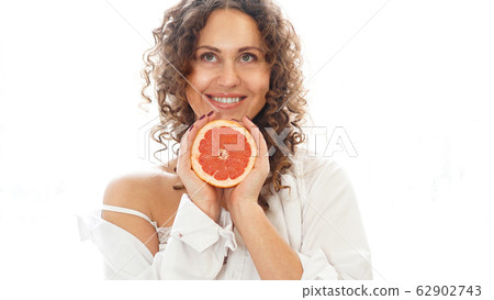 Portrait of pretty middle-aged woman with curly hair with grapefruit 62902743