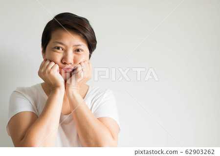Portrait of a woman uses two hands prop up her chin and looks at the front of her with feeling bore. Portrait of a woman uses two hands prop up her chin and looks at the front of her with feeling bore. 62903262