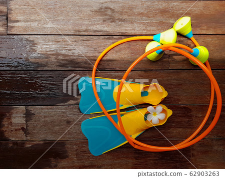 Top view of colorful flippers and toy swimming aid for kid diving practice on wooden background. Top view of colorful flippers and toy swimming aid for kid diving practice on wooden background. 62903263