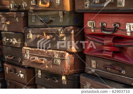 Wall of vintage suitcases stacked in a heap. 62903710