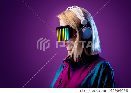Blonde in VR glasses and headphones on pink 62904088