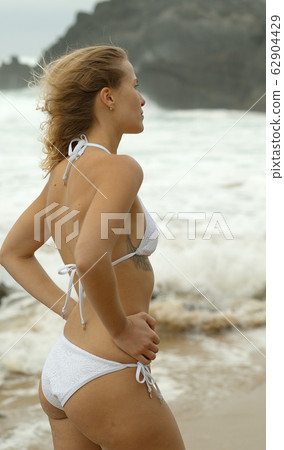 Beautiful woman poses for the camera on a beach at the ocean 62904429