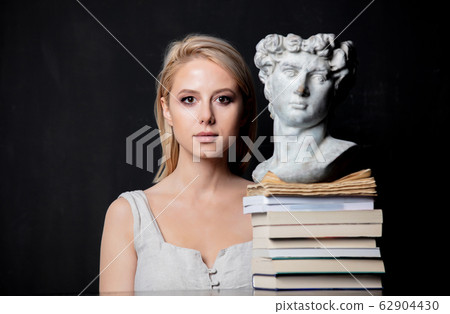 blonde next to an antique bust of a man on books 62904430