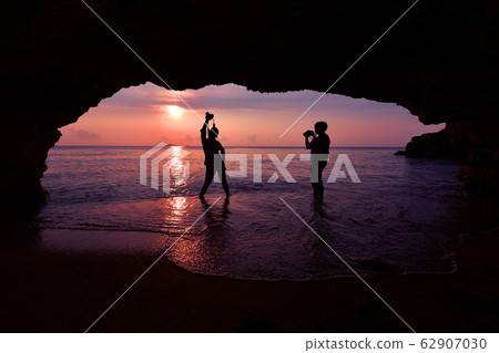 Silhouette of woman standing using camera to take 62907030