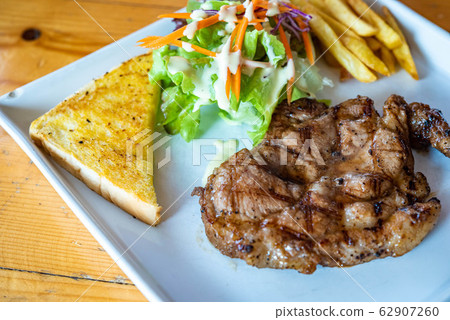 Black Pepper Pork Steak Food is popular in Asia, on a plate on a wooden floor. 62907260