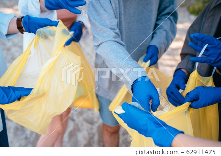 Group of activists friends collecting plastic waste on the beach. Environmental conservation. Group of activists friends collecting plastic waste on the beach. Environmental conservation. 62911475