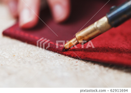 A leather craftsman works with leather. Sews A leather craftsman works with leather. Sews 62911694