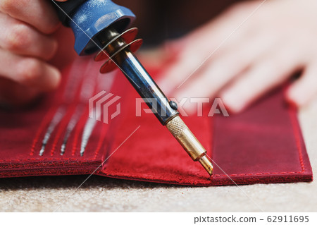 A leather craftsman works with leather. Sews A leather craftsman works with leather. Sews 62911695
