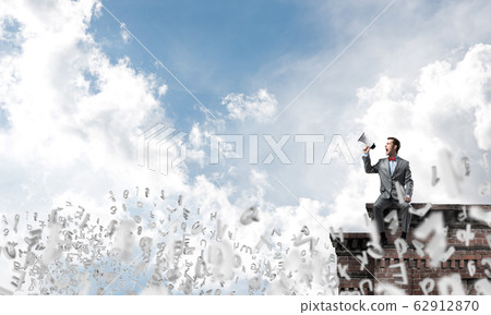 Businessman in summer park announcing something in loudspeaker and symbols fly around Businessman in summer park announcing something in loudspeaker and symbols fly around 62912870