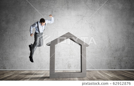 Stone home silhouette in empty room as symbol for real estate insurance Stone home silhouette in empty room as symbol for real estate insurance 62912876