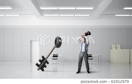 Breaking through access concept with furious man crashing concrete key Breaking through access concept with furious man crashing concrete key 62912979
