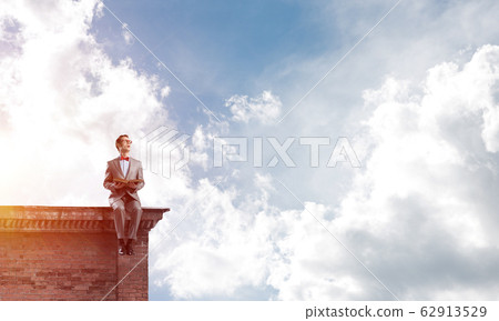Young businessman or student studying the science on building roof Young businessman or student studying the science on building roof 62913529