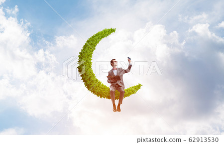 Young businessman or student on moon in sky studying the science 62913530