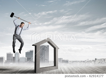 Manager man crashing stone home as symbol for real estate insurance Manager man crashing stone home as symbol for real estate insurance 62914177