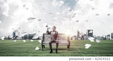 Businessman in summer park announcing something in loudspeaker a Businessman in summer park announcing something in loudspeaker a 62914322
