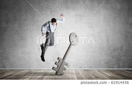Breaking through access concept with man in room crashing concrete key 62914436