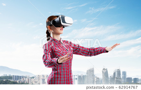 Girl in checked shirt wearing VR glasses experiencing another reality 62914767