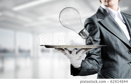 Hand of waitress presenting lightbulb on tray. 62914844