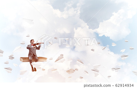 Handsome violinist play his melody and paper planes fly around Handsome violinist play his melody and paper planes fly around 62914934