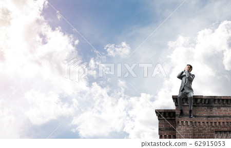 Young man on building edge do not want to see anything Young man on building edge do not want to see anything 62915053