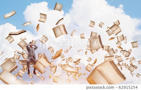 Young man on pile of books dont want to hear anything 62915254