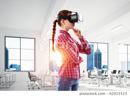 Girl in virtual reality mask experiencing virtual technology world. Mixed media 62915523