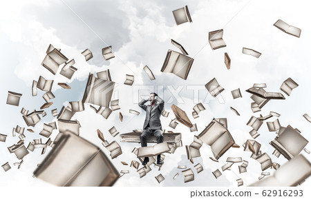 Young man on pile of books dont want to hear anything 62916293