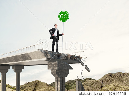 Young businessman holding street safety sign. Young businessman holding street safety sign. 62916336