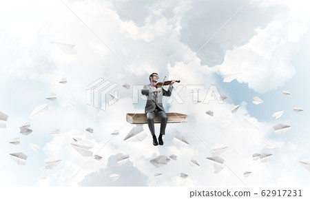 Handsome violinist play his melody and paper planes fly around Handsome violinist play his melody and paper planes fly around 62917231