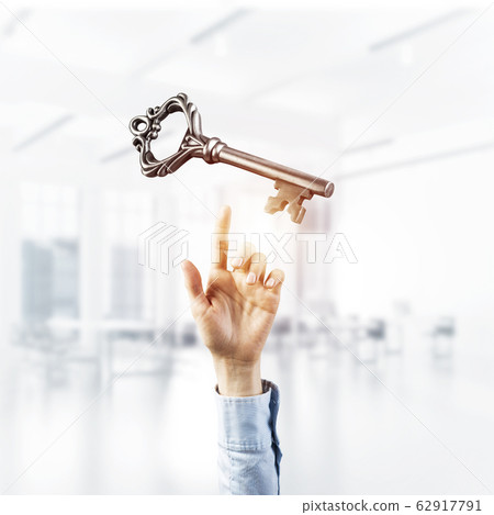 Retro metal key and male palm against office interior. Mixed med 62917791