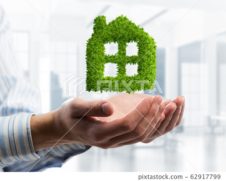 Housing or mortgage idea with green house symbol in male palms. Mixed media 62917799