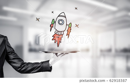 Hand of waiter presenting sketched rocket on tray Hand of waiter presenting sketched rocket on tray 62918387