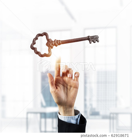 Retro metal key and male palm against office interior. Mixed med Retro metal key and male palm against office interior. Mixed med 62918671