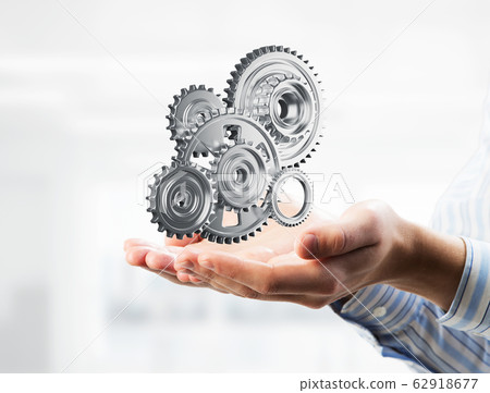 Engine mechanism in male ahnds as symbol for cooperation or teamworking. Mixed media Engine mechanism in male ahnds as symbol for cooperation or teamworking. Mixed media 62918677
