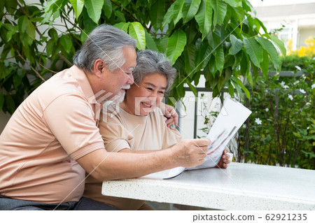 Asian senior couple laughing while reading Asian senior couple laughing while reading 62921235