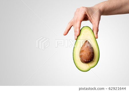 Avocado in hand on grey background. Vegetarian food and vitamins Avocado in hand on grey background. Vegetarian food and vitamins 62921644