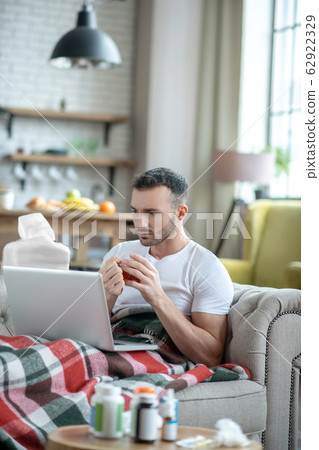 Dark-haired young man laying on the sofa feeling sick 62922329